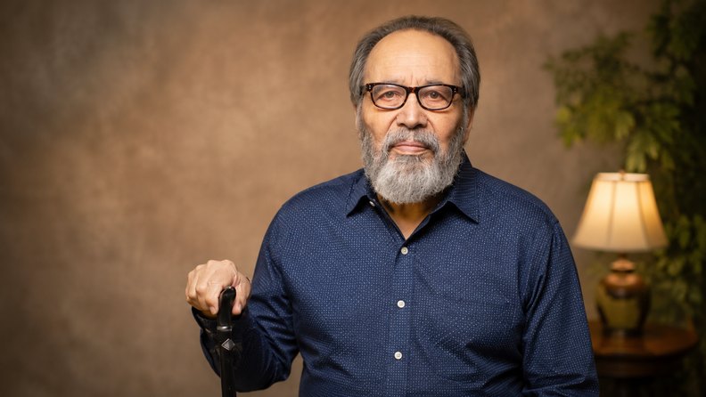 Portrait of an older man standing with a walking cane